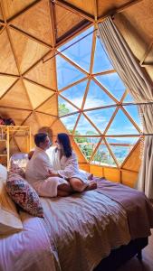 um homem e uma mulher sentados numa cama numa tenda em Cabanas Bela Vista em São Bento do Sapucaí