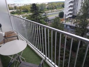 a balcony with a white railing and a table and chair at Puteaux - PARIS LA DEFENSE in Puteaux