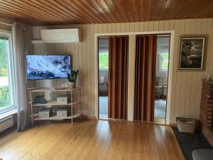 a living room with a tv and a wooden floor at Stuga Sövde in Sövde