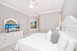 a white bedroom with a bed and a flat screen tv at On the Bay #103 Condo in Old Man Bay