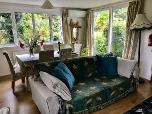 uma sala de estar com um sofá, uma mesa e janelas em Fuchsia Cottage em Porthallow