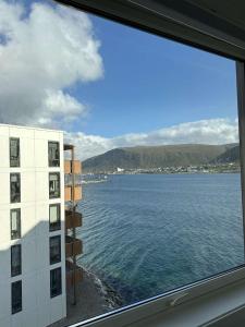 a view of the water from a window of a building at Seaside panorama in Tromsø