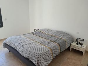 a bed in a bedroom with a white wall at Maison en plein nature in Villemus