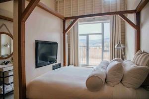una camera da letto con un letto, una TV e una finestra di Hôtel & Spa Le Germain Charlevoix a Baie-Saint-Paul
