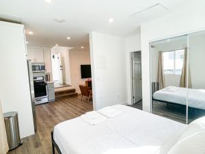 a white bedroom with two beds and a kitchen at Cozy Habitat in Los Angeles