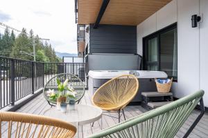 balcón con mesa, sillas y bañera en Western Star by Revelstoke Vacations, en Revelstoke