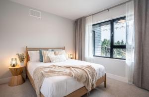 a white bedroom with a bed and a window at Western Star by Revelstoke Vacations in Revelstoke