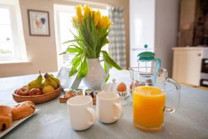einen Tisch mit einem Glas Orangensaft und einer Vase Blumen in der Unterkunft East Ayrlow Banks in Hauxwell