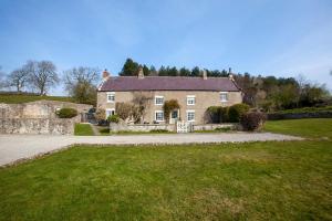 a large house with a stone wall and a yard at East Ayrlow Banks in Hauxwell