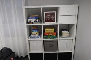 a white book shelf with books on it at Kur palikt Salacgrīvā in Salacgrīva