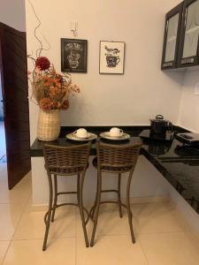 uma cozinha com uma mesa com duas cadeiras e um vaso com flores em Studio Lindo no coração de Picos em Picos