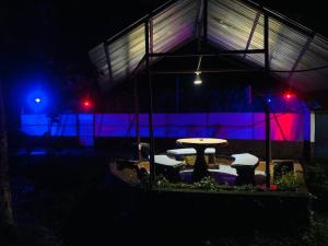 a table and chairs in front of a building at night at Cabina Rainforest , Valle Azul - Near Fortuna Arenal Volcano in San Lorenzo