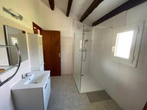a white bathroom with a shower and a sink at Résidences Anna in Centuri