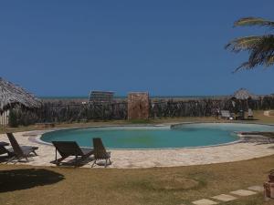 a swimming pool with two chairs and the ocean in the background at Vista do paraíso AP 09 Condomínio vilas na Praia Residente in Canoa Quebrada