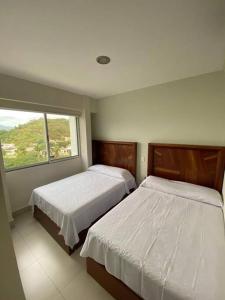 曼萨尼约HERMOSO DEPARTAMENTO DE LUJO EN MANZANILLO A PIE DE PLAYA EN PONTO HORIZONTE MANZANILLO. PARA HASTA 8 PERSONAS, DE LO MEJOR DE MANZANILLO. HERMOSA VISTA AL MAR的有两张床和一扇窗户的卧室