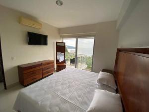 曼萨尼约HERMOSO DEPARTAMENTO DE LUJO EN MANZANILLO A PIE DE PLAYA EN PONTO HORIZONTE MANZANILLO. PARA HASTA 8 PERSONAS, DE LO MEJOR DE MANZANILLO. HERMOSA VISTA AL MAR的带床、梳妆台和窗户的卧室
