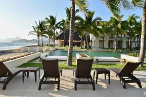 曼萨尼约HERMOSO DEPARTAMENTO DE LUJO EN MANZANILLO A PIE DE PLAYA EN PONTO HORIZONTE MANZANILLO. PARA HASTA 8 PERSONAS, DE LO MEJOR DE MANZANILLO. HERMOSA VISTA AL MAR的一个带椅子、游泳池和棕榈树的度假村