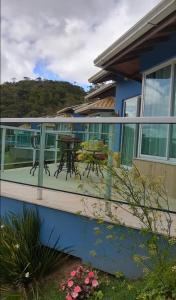 uma casa azul com um deque com uma mesa e cadeiras em Pousada Casa no Sitio em Santa Teresa