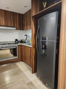 a kitchen with a stainless steel refrigerator and a stove at Hermoso y nuevo departamento en Nuevo Vallarta in Jarretadera