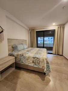 a bedroom with a bed and a large window at Hermoso y nuevo departamento en Nuevo Vallarta in Jarretadera