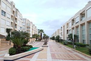 an empty street with apartment buildings and palm trees at Feeling Home Garden Apartment in Herzliya