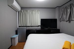 a bedroom with a white bed and a television at TOKYO HOUSE INN - Vacation STAY 51871v in Tokyo