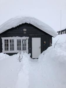 a house covered in snow with a pile of snow at Osetunet, small and charming cabin at Ustaoset in Ustaoset
