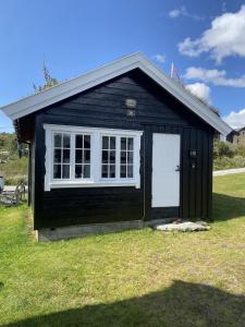 a black shed with a white door and a window at Osetunet, small and charming cabin at Ustaoset in Ustaoset