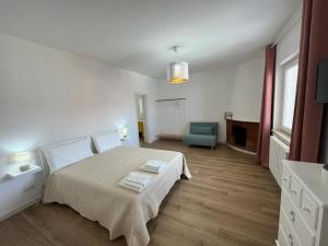 a white bedroom with a bed and a blue chair at Il Riccio in Bari