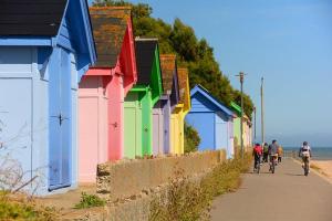 a group of people riding bikes down a sidewalk next to colorful buildings at Folkestone 3 Bedroom with private parking and EV car outlet near M20 easy access to Eurotunnel, Dover & Dungeoness in Sandgate