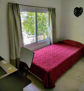 Un dormitorio con una cama roja y una ventana. en Bello Dpto, 20 minutos al Estadio Kempes, cerca de Quality, Hospital Privado, en Córdoba