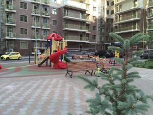 un parque con parque infantil con tobogán y banco en Arkhitektorska Apartment, en Odessa