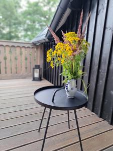 a vase of flowers sitting on a table on a deck at Czerwone Drzwi in Stronie Śląskie