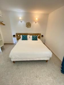 a bedroom with a large white bed with blue pillows at Résidences Anna in Centuri