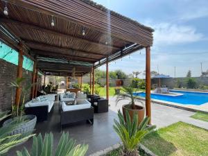 uma pérgola de madeira com sofás e uma piscina em Casa Pachacamac em Lima