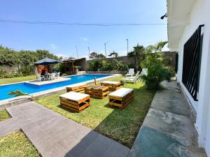 Casa en San Fernando Pachacamac في ليما: حديقة خلفية بها مسبح به طاولات وكراسي