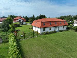 a house with a red roof on a green yard at Comfortable holiday home with a private garden, 200 sqm, 5 bedrooms, Dar owo in Darłowo