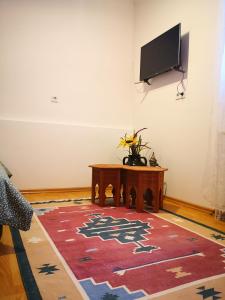 een woonkamer met een tafel en een tv aan de muur bij Apartment Bistrik 1 in Sarajevo