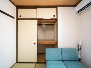 Habitación con armario y sofá azul. en maison elegance - Vacation STAY 15341, en Tokio