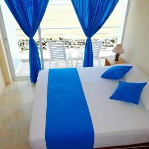 a bedroom with a bed with blue curtains and a balcony at Hotel Crucero in Cojimíes