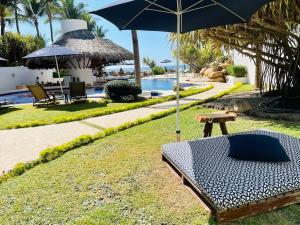 una panchina con ombrellone accanto alla piscina di Exclusivo Departamento con acceso a playa ad Acapulco