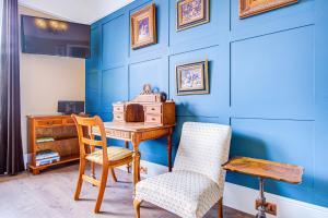 a blue room with a wooden desk and a chair at A Quaint and Delightful Abode in Normanhurst in Carshalton