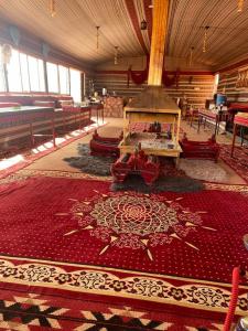 ワディ・ラムにあるOmar Ghazi Campの暖炉と赤い敷物が備わる広い客室です。