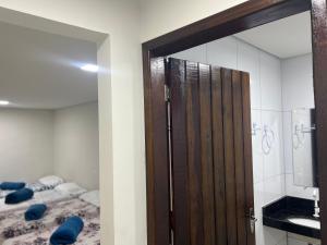 ein Bad mit einer Holztür und einem Bett in der Unterkunft Acomodação aconchegante próximo ao centro in Garanhuns