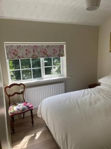 a bedroom with a bed and a chair and a window at Millview Cottage in Castledawson