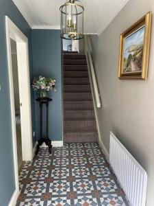 a hallway with a staircase with blue walls and a stair case at Millview Cottage in Castledawson