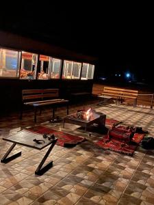 a fire pit and benches on a patio at night at Omar Ghazi Camp in Wadi Rum