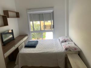 a small bedroom with a bed and a window at Apartamento na Praia do Campeche in Florianópolis