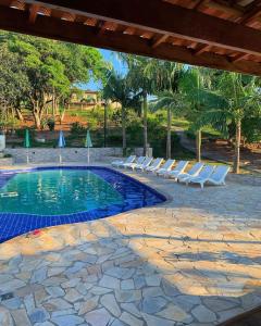 a swimming pool with lounge chairs next to a resort at Chalé Alto da Serra SP in Serra Negra