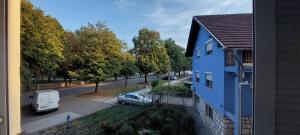 a blue house with a car parked next to a street at Stan na dan - Apartmani Q in Doboj